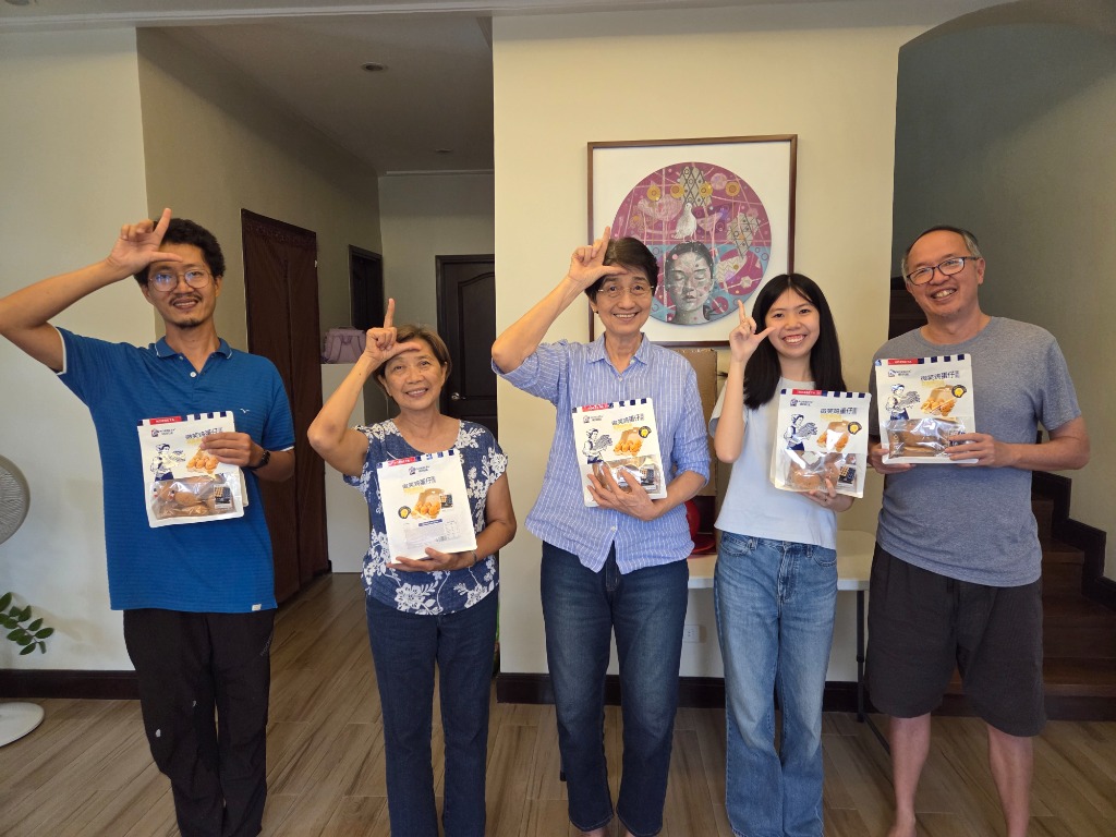 Family members playfully posing with L hand gestures on foreheads and egg roll snack packs